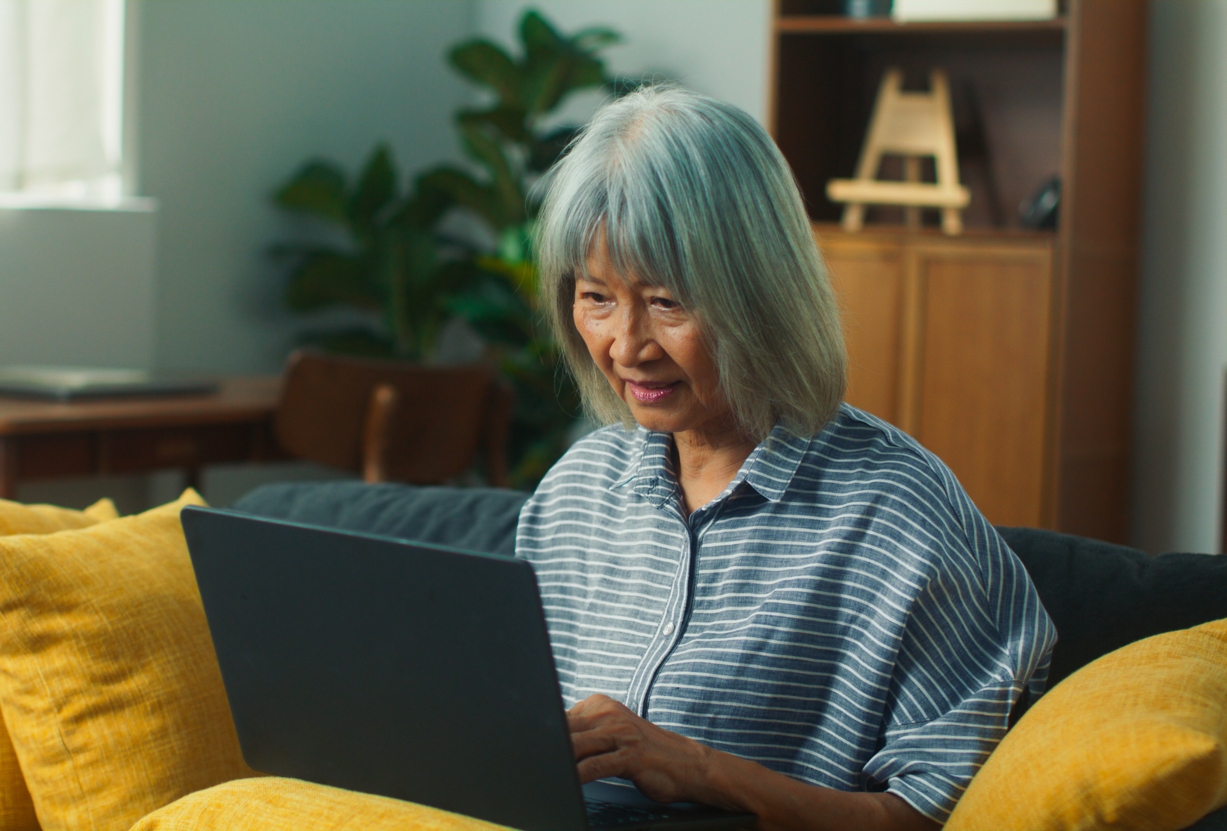 Femme qui consultent de l'information sur l'ordinateur assise sur le canapé